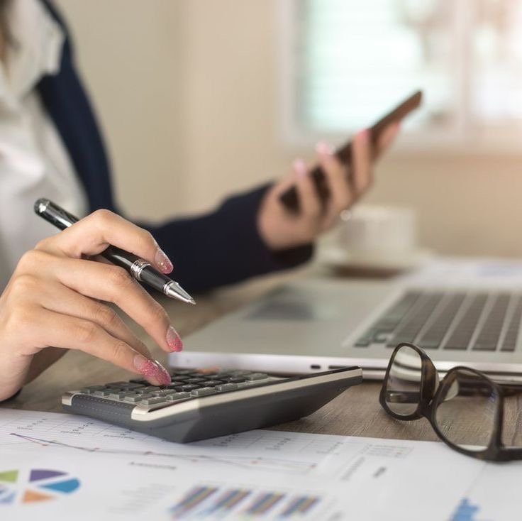 Rotina financeira manual: calculadora, celular e relatórios sobre a mesa